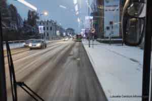 Widok ze środka autobusu na zaśnieżoną drogę.